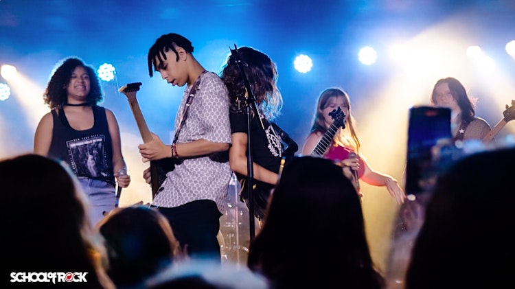 Teen playing guitar in School of Rock's Performance Program